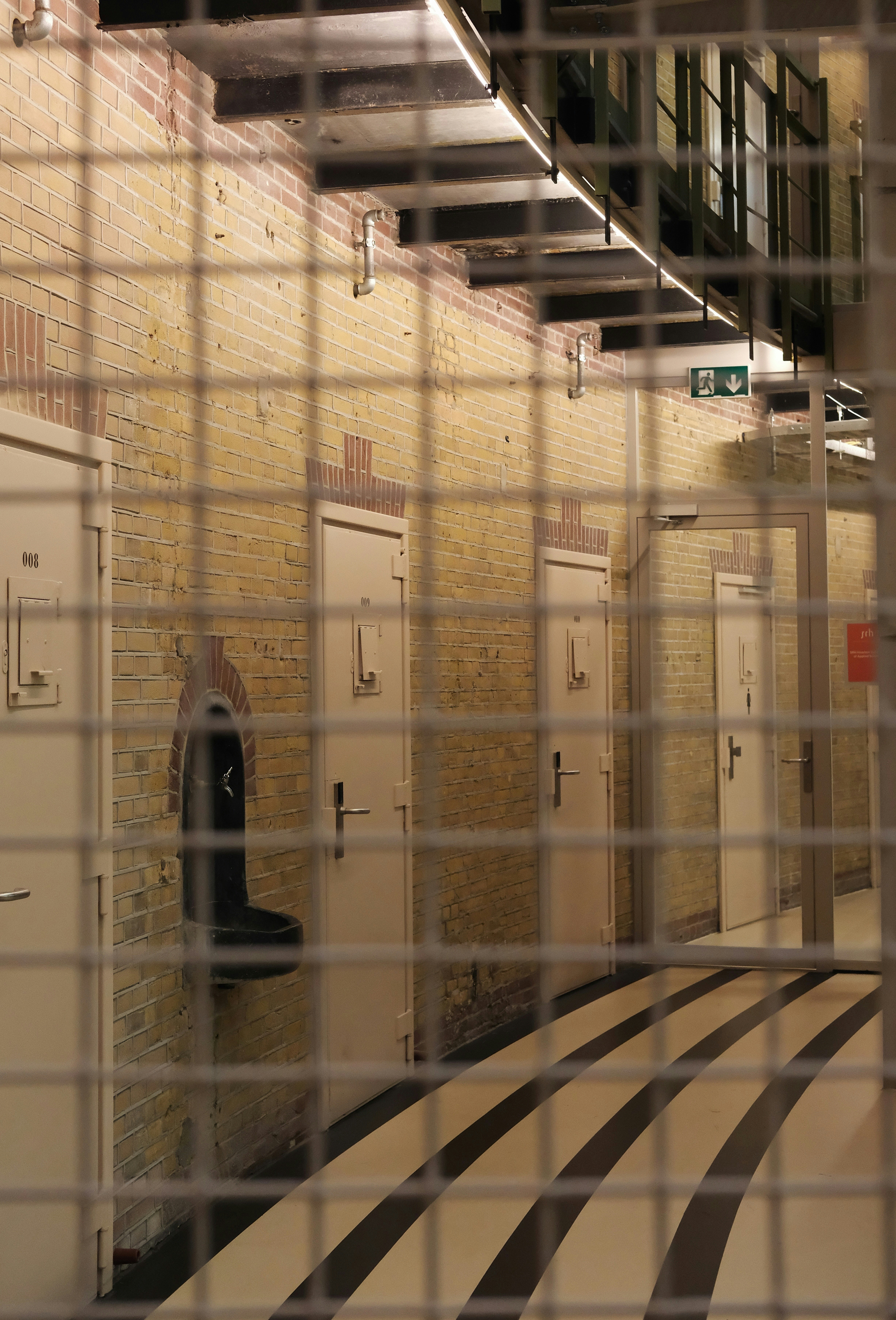 Former prison corridor with cell doors behind a metal grille