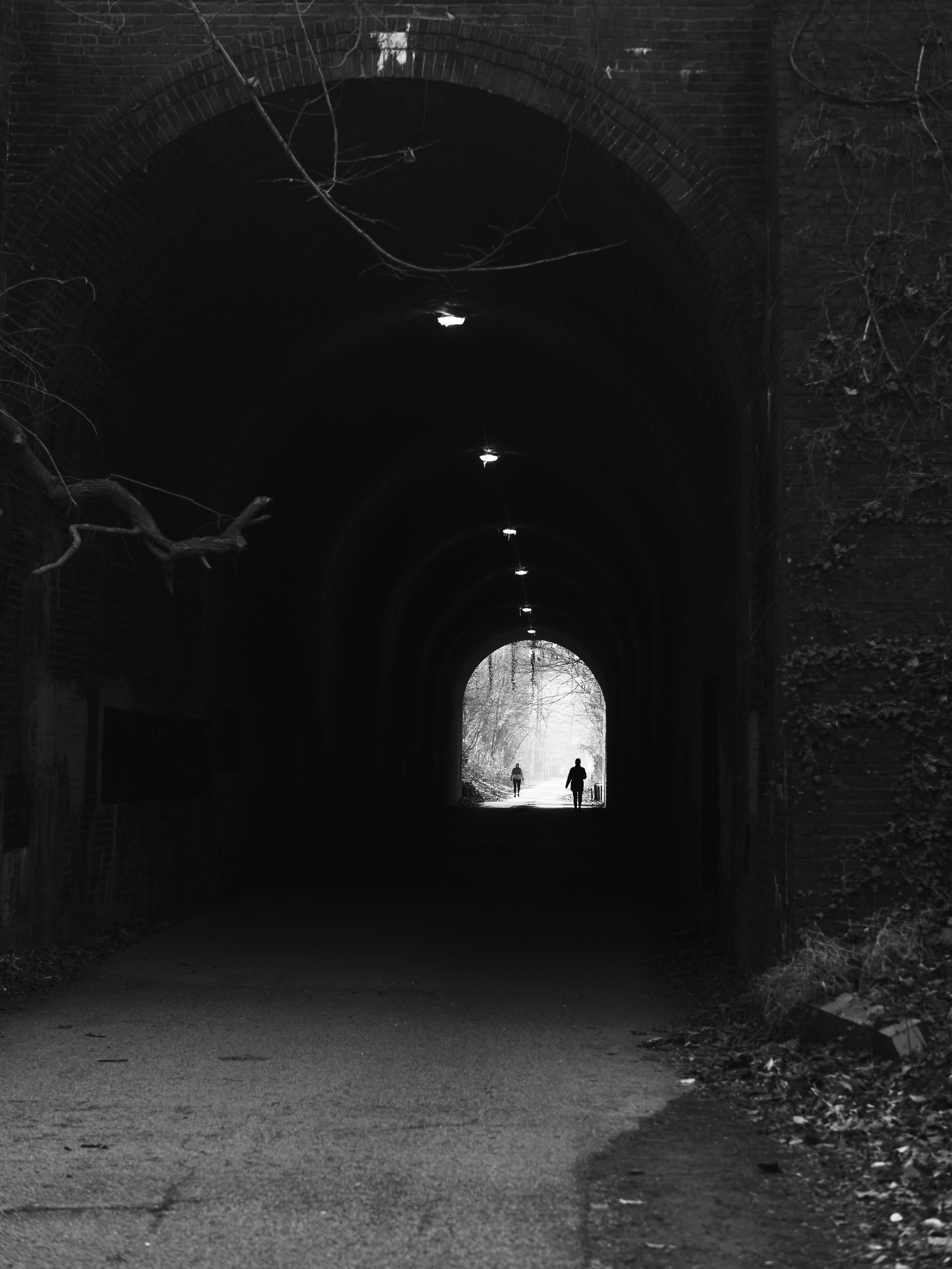 Photo by Sebastian Schuster on Unsplash Two figures walk through a dark arched tunnel
